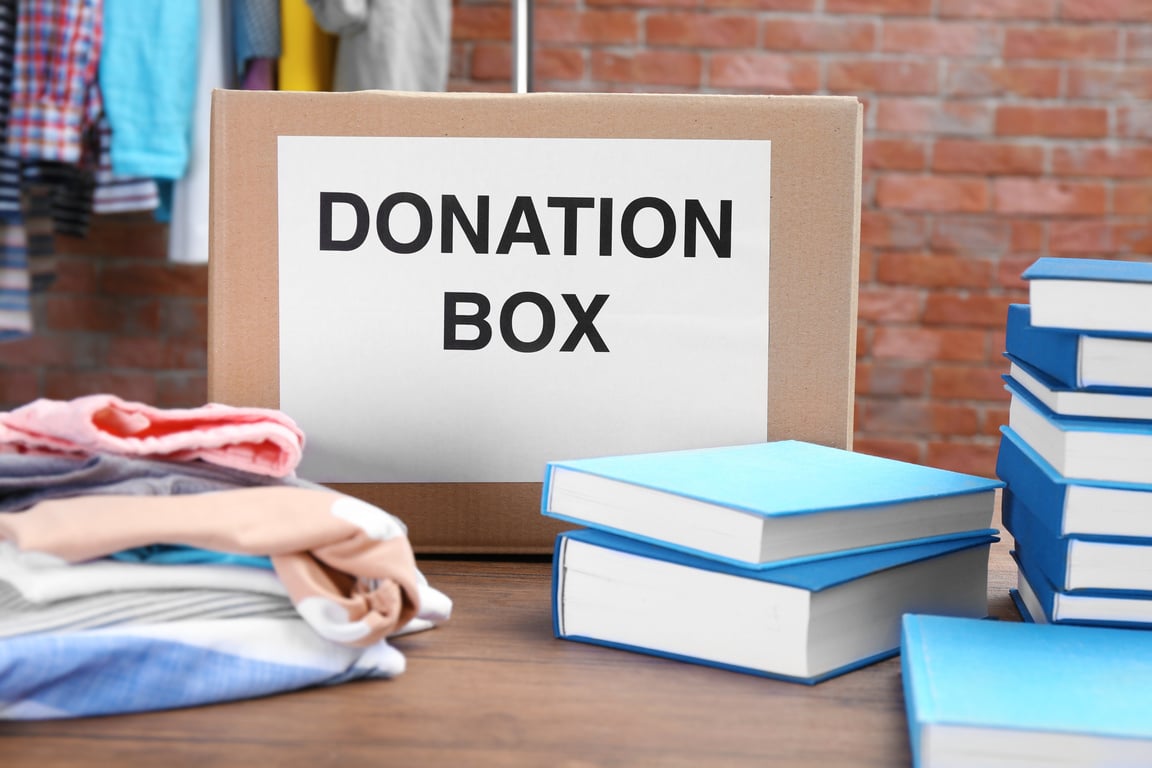 Donation Box with Clothes and Books on Table 